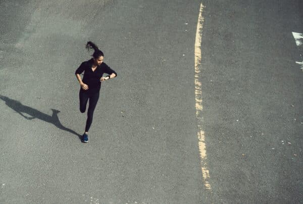 Een vrouw kijkt hardlopend op haar horloge - sneller hardlopen - RunX