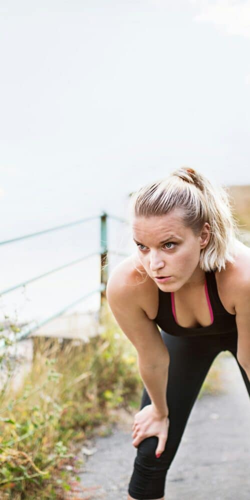 Vrouw aan het uitrusten na het hardlopen aan de waterkant - herstel na hardlopen - RunX