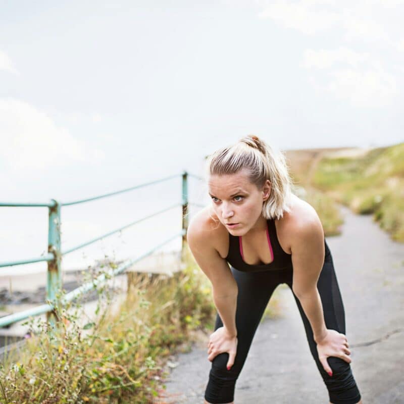 Vrouw aan het uitrusten na het hardlopen aan de waterkant - herstel na hardlopen - RunX