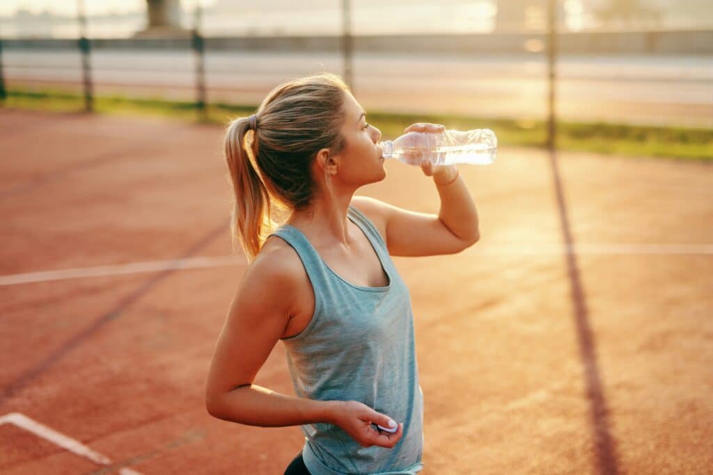Vrouw-neemt-pauze-tijdens-hardlopen-met-warm-weer-en-hydrateert-met-een-waterfles