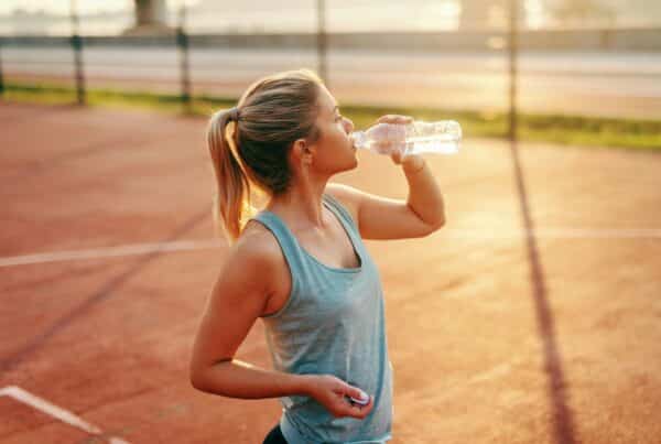Vrouw-neemt-pauze-tijdens-hardlopen-met-warm-weer-en-hydrateert-met-een-waterfles