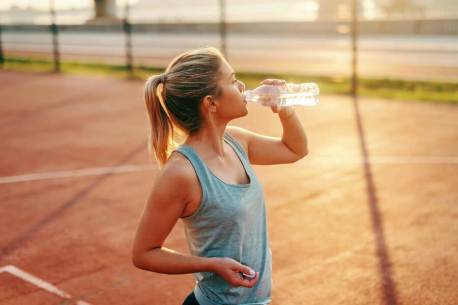 Vrouw-neemt-pauze-tijdens-hardlopen-met-warm-weer-en-hydrateert-met-een-waterfles